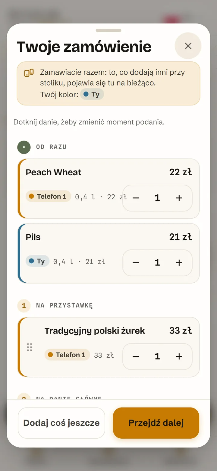 Wspólny koszyk stołu na telefonie: pozycje dodane przez dwie osoby, każda w swoim kolorze, podzielone na biegi